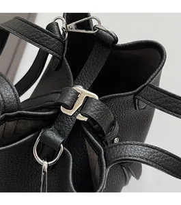 Detail of silver metal twist lock and lychee leather texture on a black bucket bag