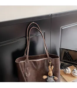 Dettaglio della borsa tote vintage marrone scuro con ciondolo a coniglietto scozzese