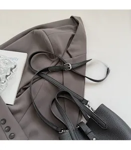Detail of adjustable silver buckle on black lychee grain leather shoulder strap