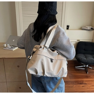 Detail of a large beige canvas tote bag with wide straps shown on model back