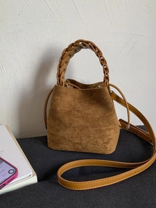 Brown suede bucket bag with stylish woven chain handle and thin shoulder strap