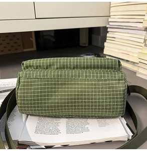 Detail of green checkered nylon tote bag placed on books in a casual lifestyle setting