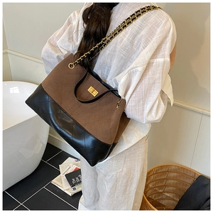 Détail d'un sac cabas vintage en daim marron et cuir matelassé noir avec bandoulière