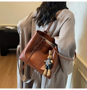Detailed side view of vintage brown leather tote bag with a cute rabbit pendant