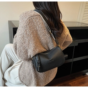 Détail du sac polochon noir avec bandoulière large tissée et pendentif à pompon