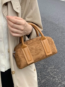 Classic tan bowling bag with smooth leather handles in a stylish outdoor street view