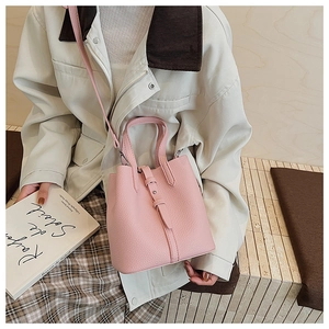 Detailed close-up of pink bucket bag featuring lychee texture and buckle strap