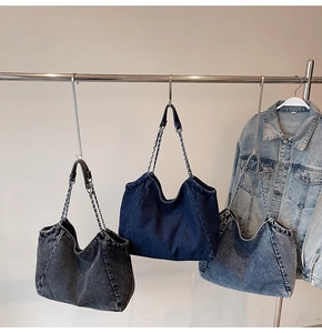 Close-up of vintage denim tote bags in black and blue with metal chain straps