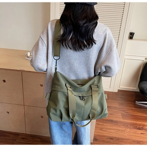 Olive green canvas messenger bag showing large capacity and adjustable shoulder strap style