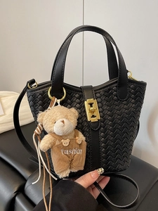 Elegante borsa a secchiello intrecciata nera con fibbia dorata e ciondolo a orsetto