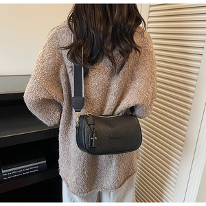 Gros plan sur le sac polochon en cuir grainé avec logo fashion et large bandoulière