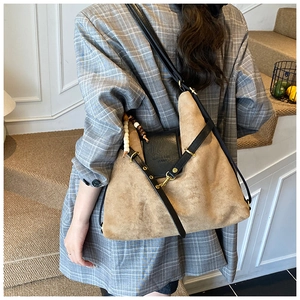 Détail d'un grand sac en daim marron avec rabat en cuir noir et charm à perles colorées