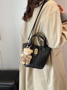 Borsa a secchiello intrecciata nera alla moda con ciondolo a orsetto e fibbia metallica