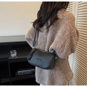 Détail d'un sac bandoulière en cuir noir avec bandoulière réglable et ferrures dorées