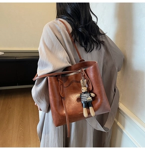 Detail of vintage brown leather tote bag with a cute bunny charm and gold fashion logo
