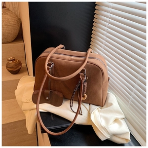 Borsa tote in pelle scamosciata marrone con pochette e ciondoli su scrivania minima
