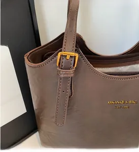 Detail of vintage brown leather shoulder bag featuring gold hardware and logo print