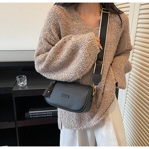 Détail du sac bandoulière en cuir noir avec large sangle et boucles dorées chic