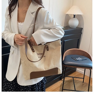 Dettaglio della borsa tote in velluto beige con manici in pelle marrone e scritta laterale