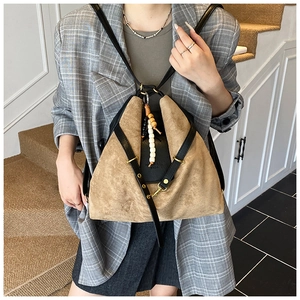 Détail du sac vintage en daim avec pendentif en perles de bois et finitions dorées