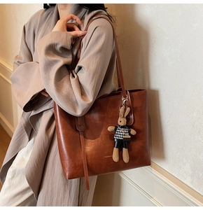 Detail of vintage brown tote bag with leather texture and cute plush rabbit charm