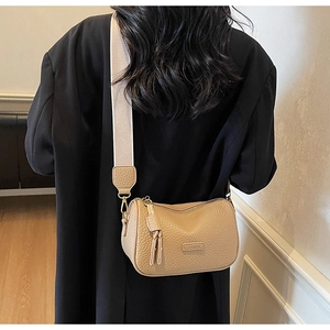 Détail d'un sac en cuir kaki grainé avec bandoulière large et fermeture à franges