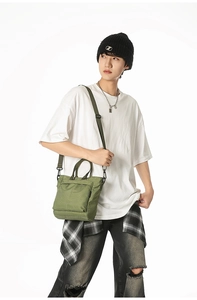 Detail of green plaid canvas tote bag with adjustable strap worn by a stylish model