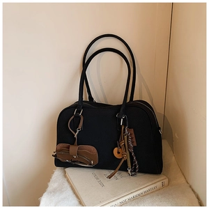 Dettaglio borsa Boston in tela nera con custodia per occhiali in pelle e ciondolo retro