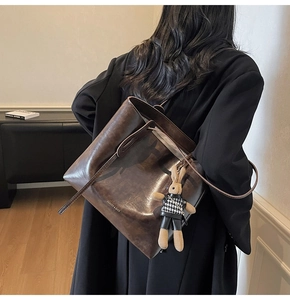 Dettaglio della borsa tote vintage marrone scuro con ciondolo a coniglio e tracolla