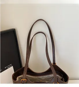 Detail of sturdy brown leather tote bag handles and secure gold zipper closure