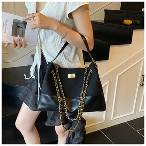 Détail du sac fourre-tout noir avec cuir matelassé, chaîne dorée et fermoir pivotant
