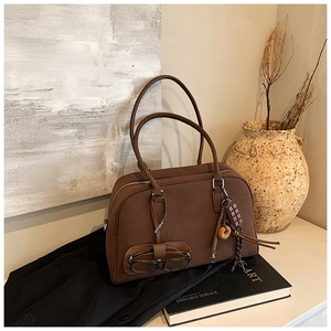 Dettaglio della borsa tote in pelle scamosciata marrone con porta occhiali e ciondoli