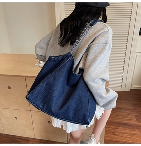 Model view of large navy denim tote bag with silver chain strap for daily wear