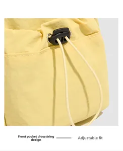 Detail of the bright yellow crossbody bag showing the front pocket drawstring buckle design