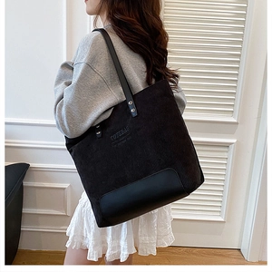 Modella che indossa una borsa tote in velluto a coste nero con base rinforzata in ecopelle