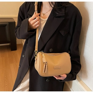 Sac bandoulière caramel avec grain de litchi porté sur un costume noir pour un style pro