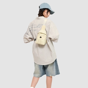 Rear view of model wearing cream nylon crossbody bag with casual striped shirt
