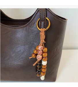 Detail of dark brown leather tote featuring retro wooden bead charms and gold logo print