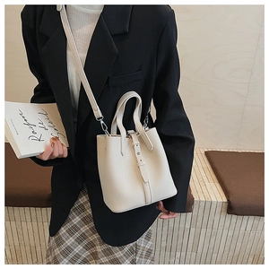 Detail view of cream white bucket bag with pebble leather texture and shoulder strap
