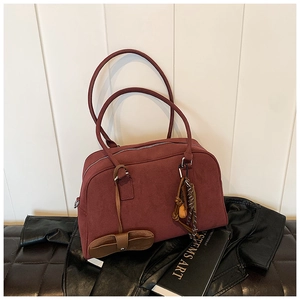 Dettaglio borsa a spalla in camoscio bordeaux con ciondoli intrecciati e zip argentata