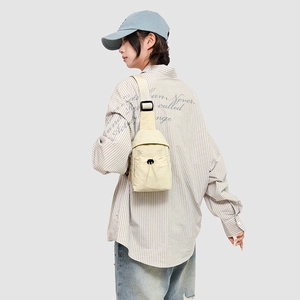 Detail view of cream nylon crossbody chest bag with adjustable strap and drawstring pocket