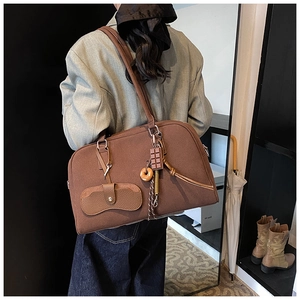 Borsa tote marrone vintage con ciondoli appesi indossata a spalla da una modella