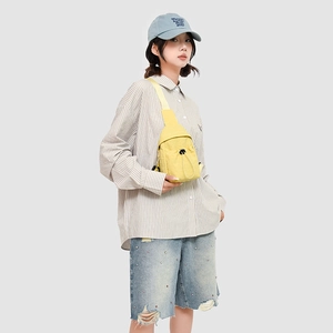 Detail of yellow canvas crossbody bag featuring front drawstring pocket and zipper closure