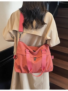 Pink canvas tote bag with adjustable strap worn by model in a stylish indoor setting