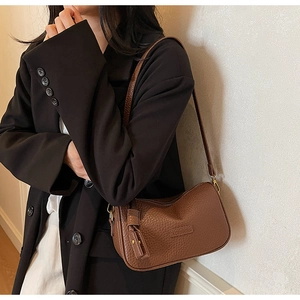 Détail de la texture cuir marron motif litchi et gland à franges sur un sac rétro chic