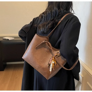 Close-up of vintage brown leather tote bag with colorful beaded tassel detail