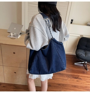 Detail shot of a large vintage denim tote bag with chain strap on a model's shoulder