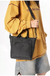 Model wearing a black checkered tote bag made of water-resistant nylon with shoulder strap