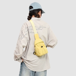 Detail view of yellow nylon crossbody bag with drawstring pocket and beige strap