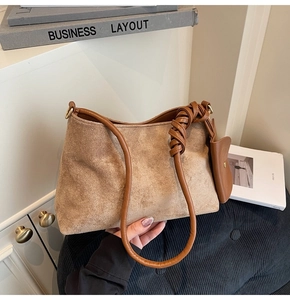 Detail of caramel suede shoulder bag with braided knot strap and mini purse charm